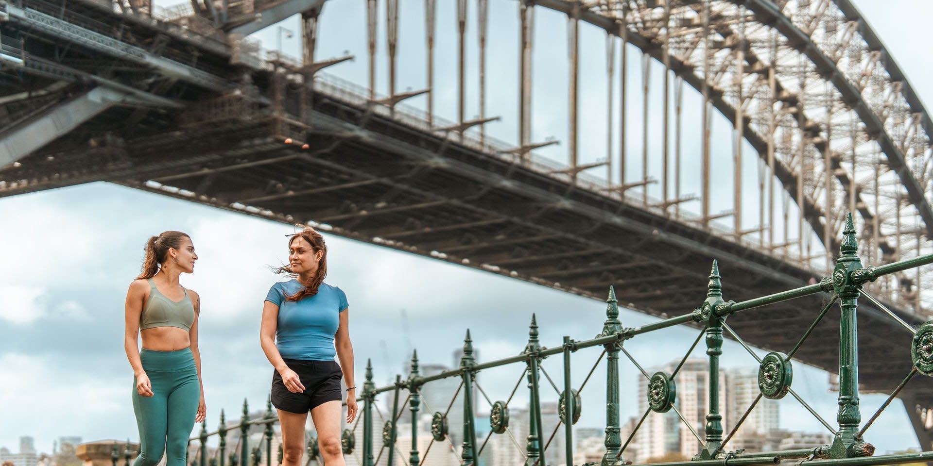 Two women walking together under the Sydney Harbour Bridge