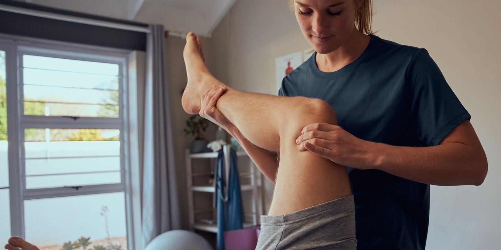 Physiotherapist stretching a patient's leg on a treatment table