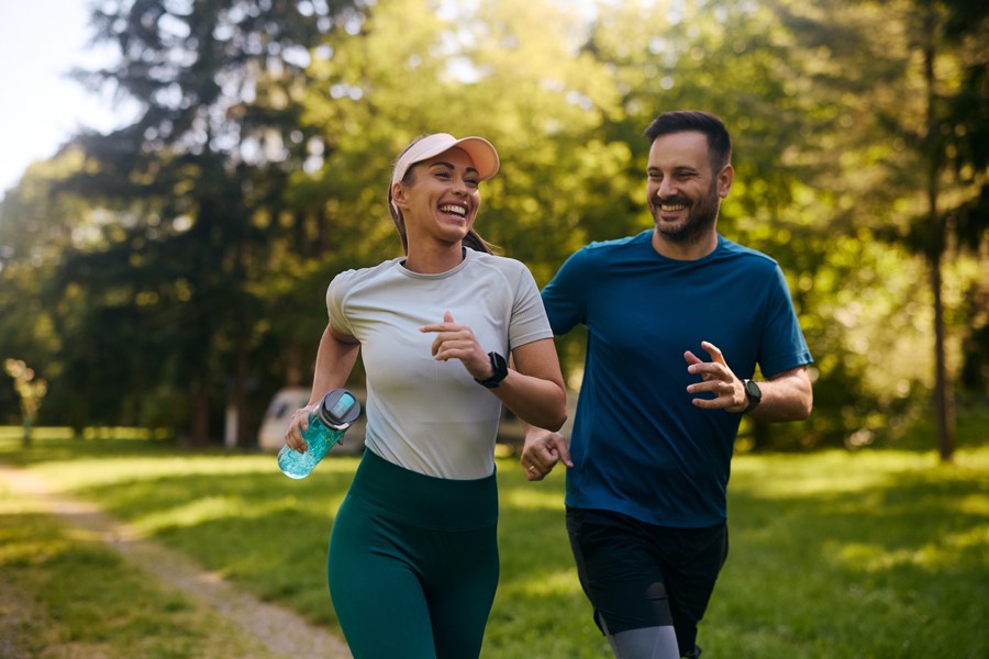 Two people running together along a park path