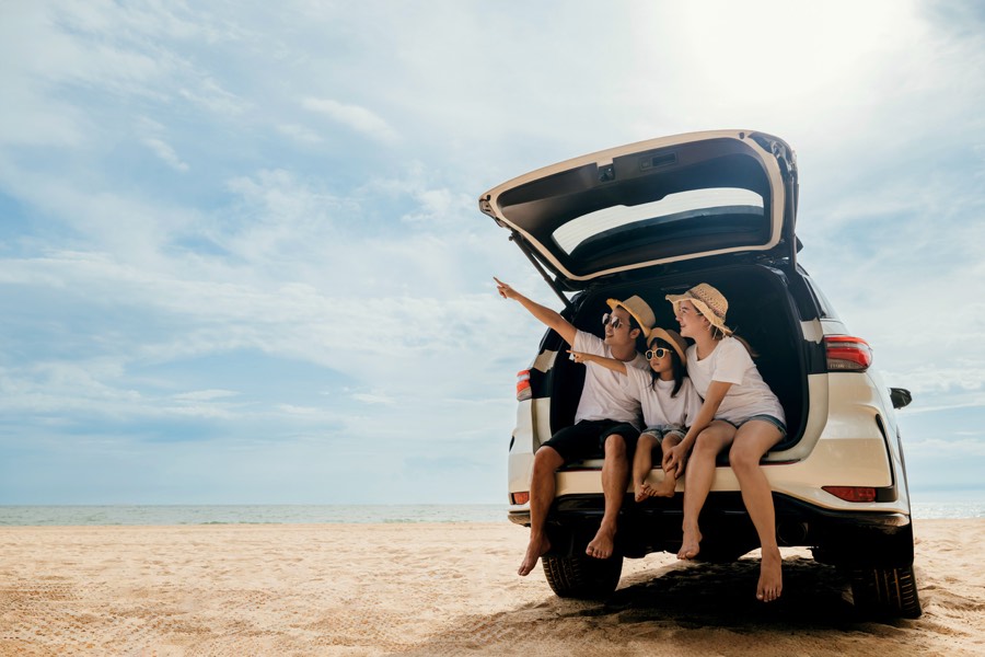 Family sitting in the boot of a car at the beach