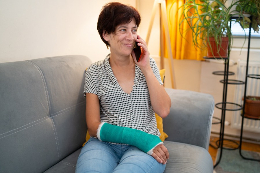 Woman with an arm cast on the phone at home